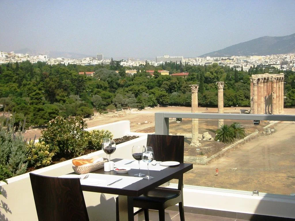 Stoly na terase The Athens Gate Hotel nad sloupy Chrámu Dia Olympského