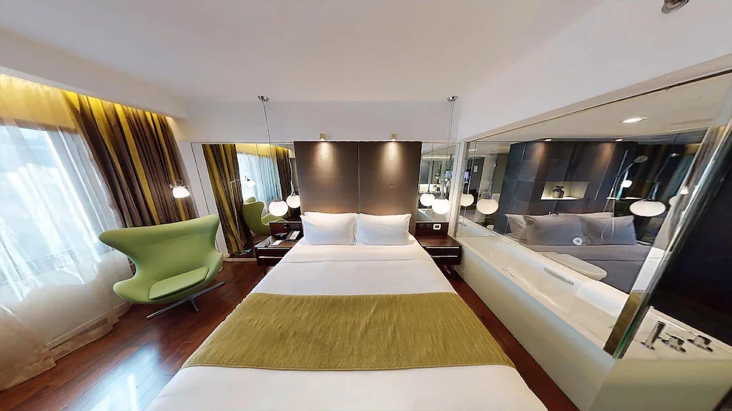 Lit double et fauteuil vert dans une City Room de The Mira