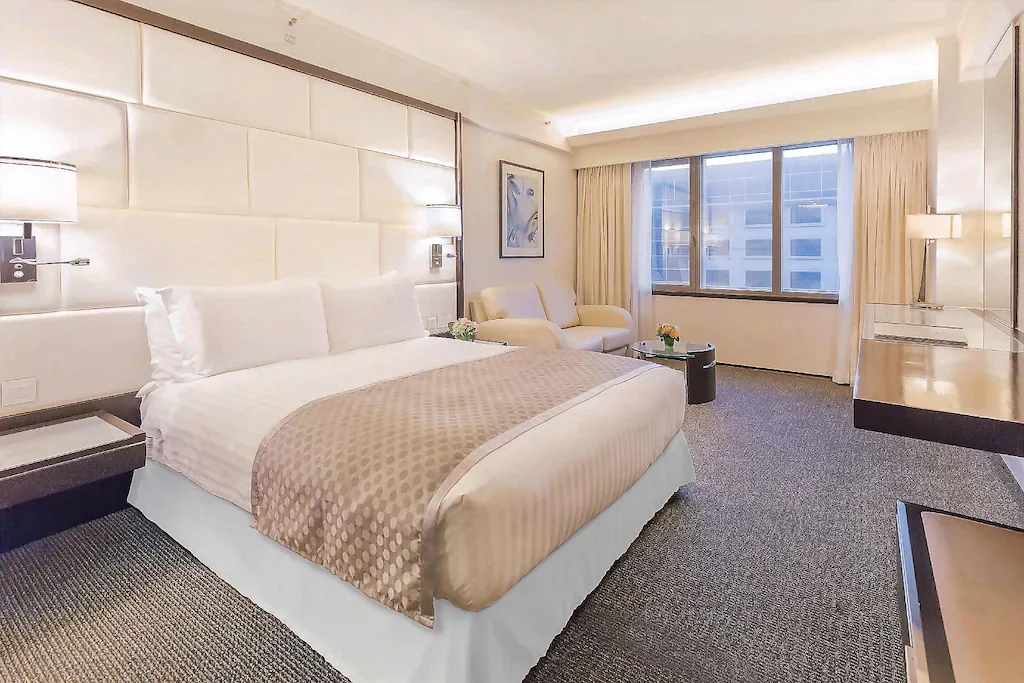เตียงหนึ่งหลังและที่นั่งริมหน้าต่างในห้อง Superior Room ของ Regal Airport Hotel