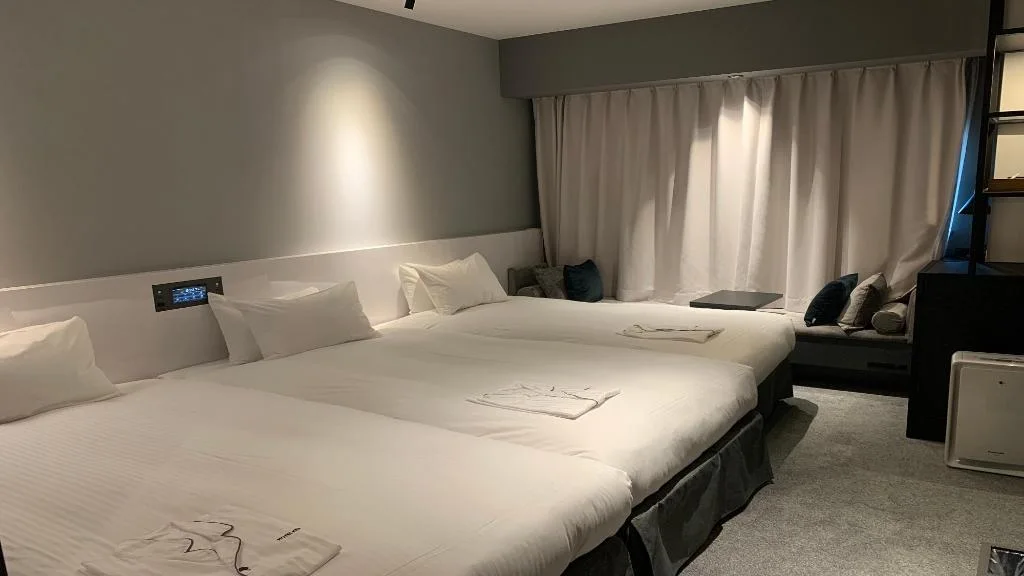 เตียงข้างม่านในห้องพักสามคนของ Hotel Keihan Namba Grande